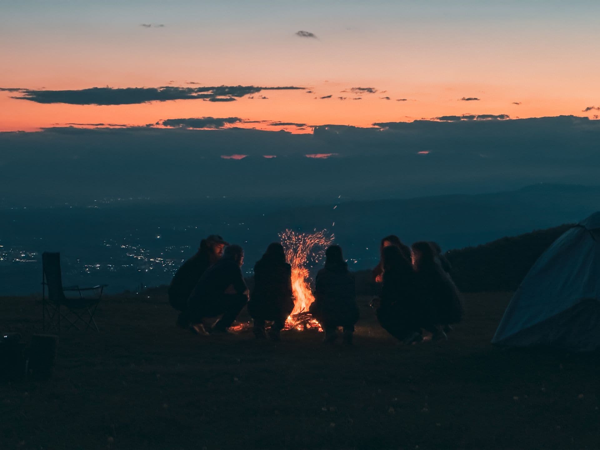 Friends around a bonfire at dusk on a mountain ridge