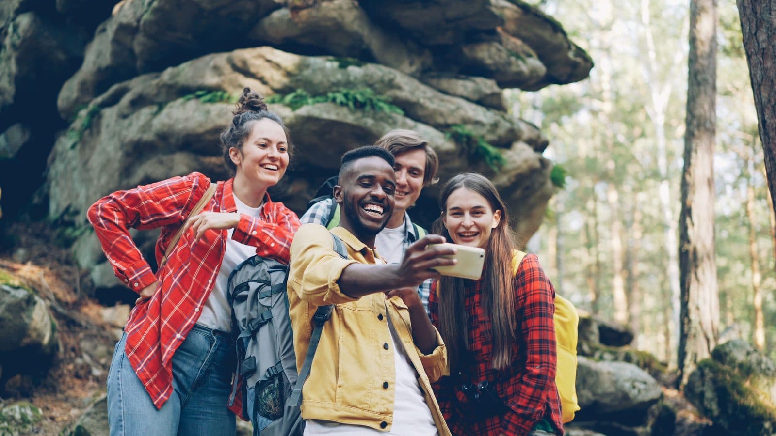 Friends laughing over a phone photo on a forest trail