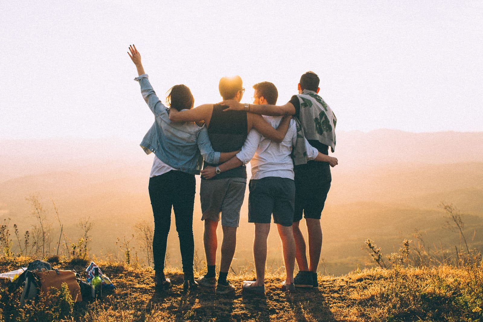 Friends with arms around each other watching a hazy sunset