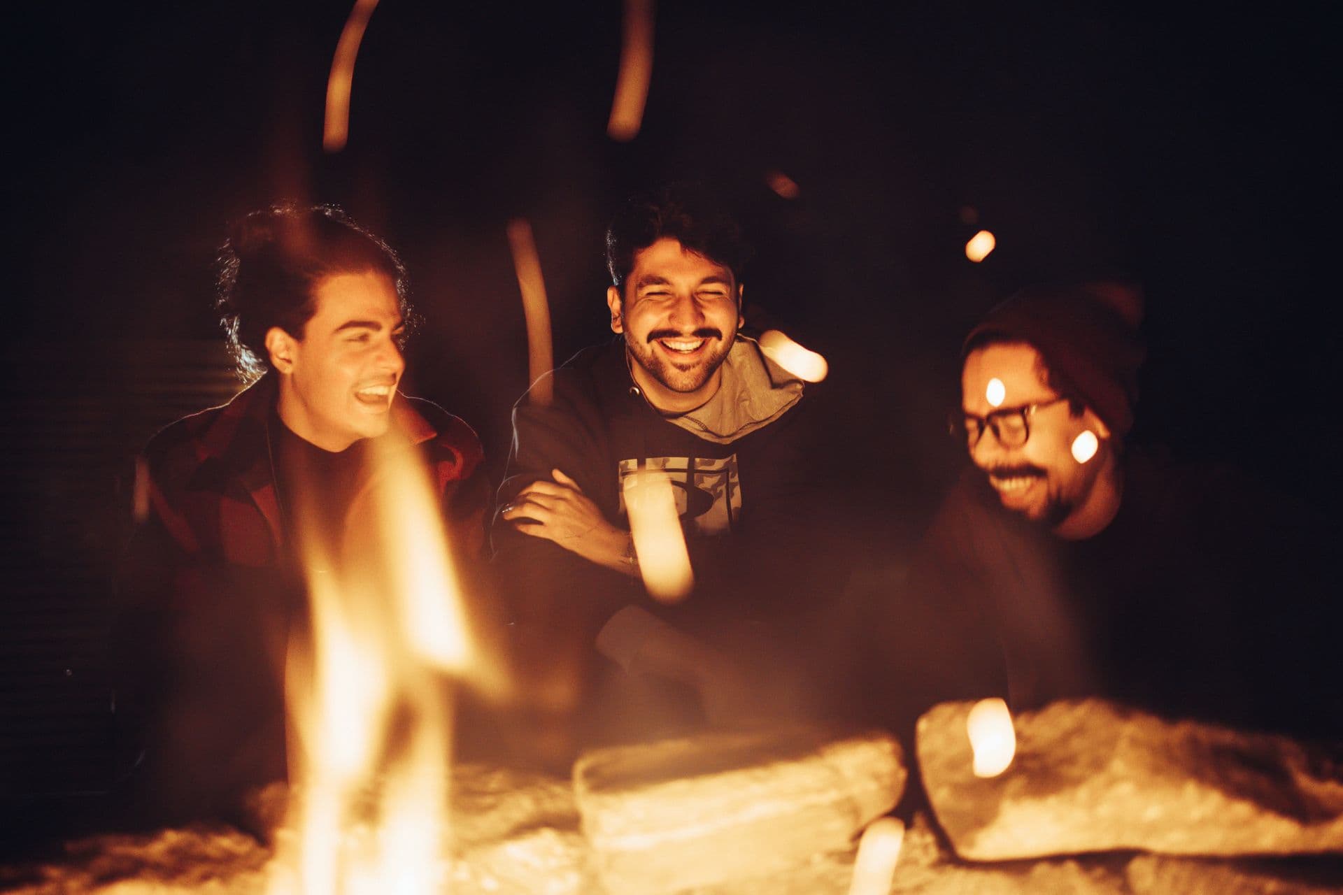 Friends laughing around a campfire with marshmallows